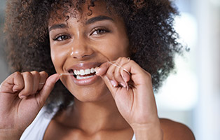 Woman with healthy smile flossing