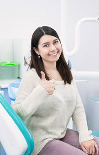 Woman in dental chair giving thumbs up 
