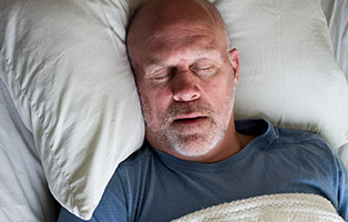 Older man sound asleep in bed