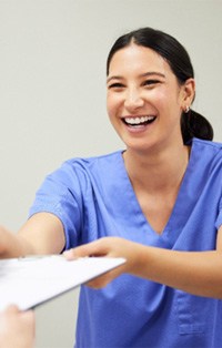 Dental assistant smiling while handing patient form
